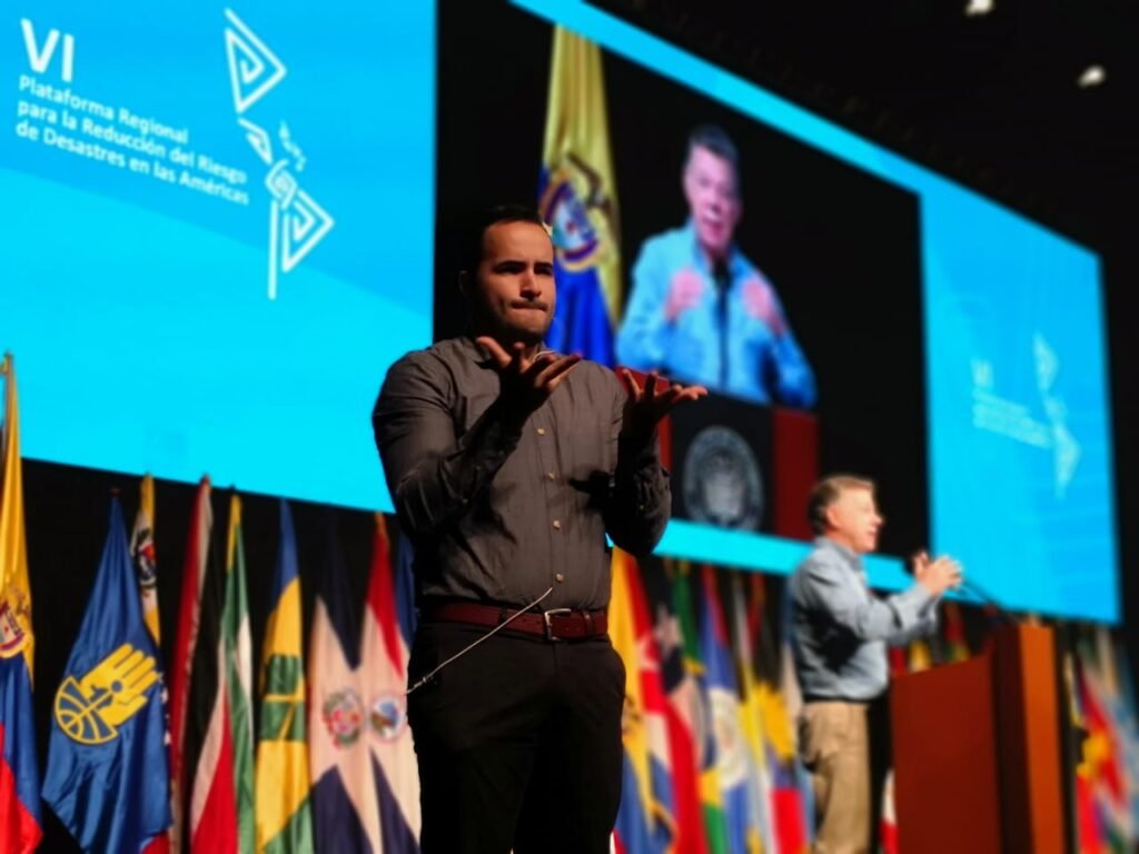 Spanish to Colombian sign language interpreter signs at international conference in Cartagena, Colombia, while Santos speaks